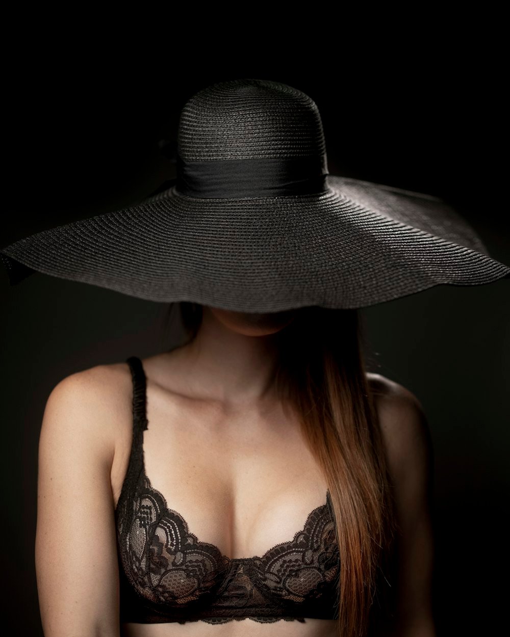 Donker boudoirportret met zwarte kanten lingerie en een brede hoed